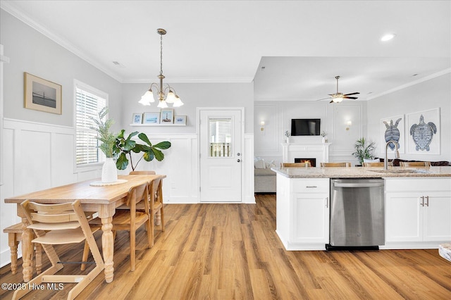 kitchen featuring a decorative wall, crown molding, light wood-style flooring, a lit fireplace, and stainless steel dishwasher