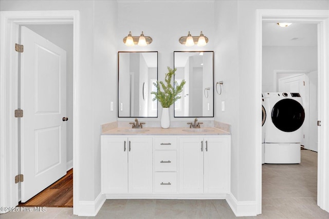 full bathroom featuring a sink, tile patterned flooring, washing machine and clothes dryer, and baseboards