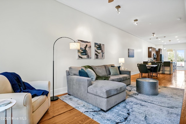 living area featuring light wood-style flooring, baseboards, and recessed lighting