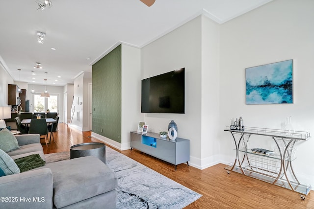 living room with baseboards, light wood-style flooring, and crown molding