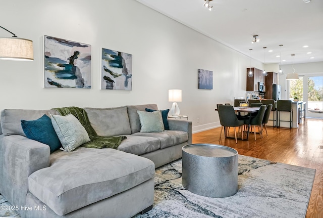 living area with light wood-style floors, baseboards, and recessed lighting