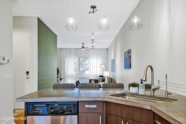 kitchen featuring a sink, open floor plan, ceiling fan, stainless steel dishwasher, and hanging light fixtures