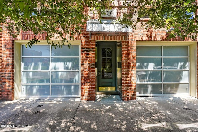 entrance to property featuring brick siding and concrete driveway