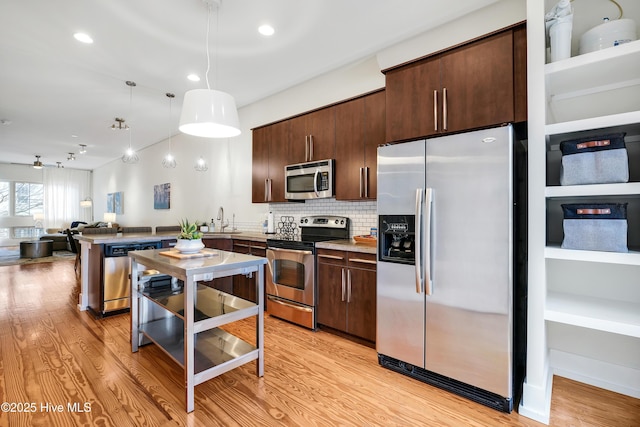 kitchen featuring stainless steel appliances, a peninsula, dark brown cabinets, tasteful backsplash, and recessed lighting