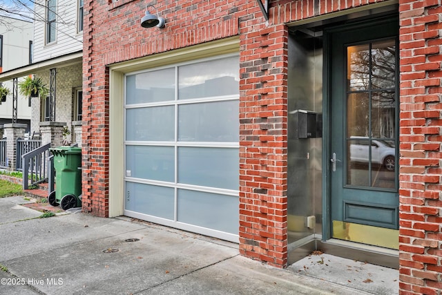 view of exterior entry with brick siding, driveway, and an attached garage