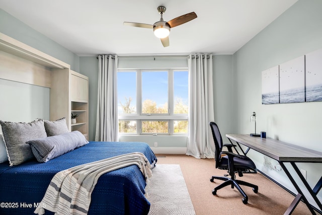 bedroom featuring light colored carpet, a desk, and a ceiling fan