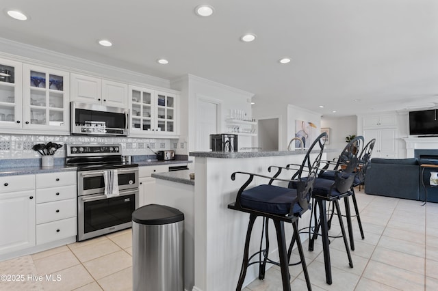 826 Fort Fisher Blvd N, Kure Beach, NC 28449 - kitchen featuring appliances with stainless steel finishes, light tile patterned floors, a breakfast bar, white cabinetry, and decorative backsplash