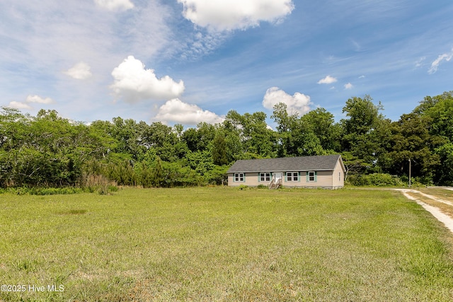 view of front of home featuring a front lawn and a wooded view