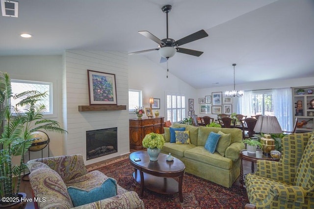 living area with vaulted ceiling, plenty of natural light, visible vents, and ceiling fan with notable chandelier