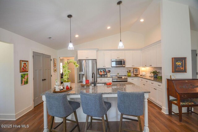 kitchen with a sink, decorative backsplash, dark wood-type flooring, stainless steel appliances, and white cabinets