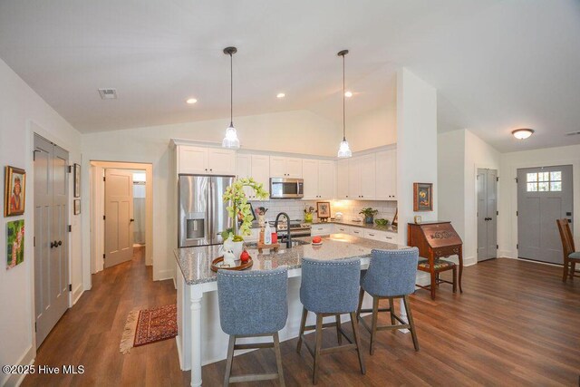 kitchen featuring light stone countertops, dark wood finished floors, white cabinetry, stainless steel appliances, and tasteful backsplash