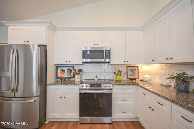 kitchen featuring white cabinets, decorative backsplash, stainless steel appliances, and wood finished floors