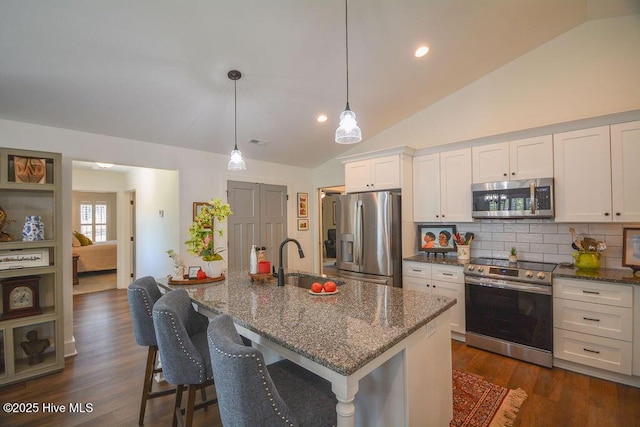kitchen with a sink, lofted ceiling, stainless steel appliances, tasteful backsplash, and white cabinetry
