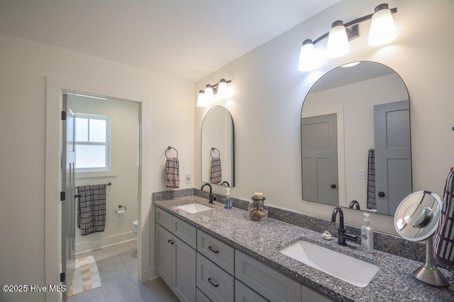 bathroom featuring double vanity, toilet, baseboards, and a sink