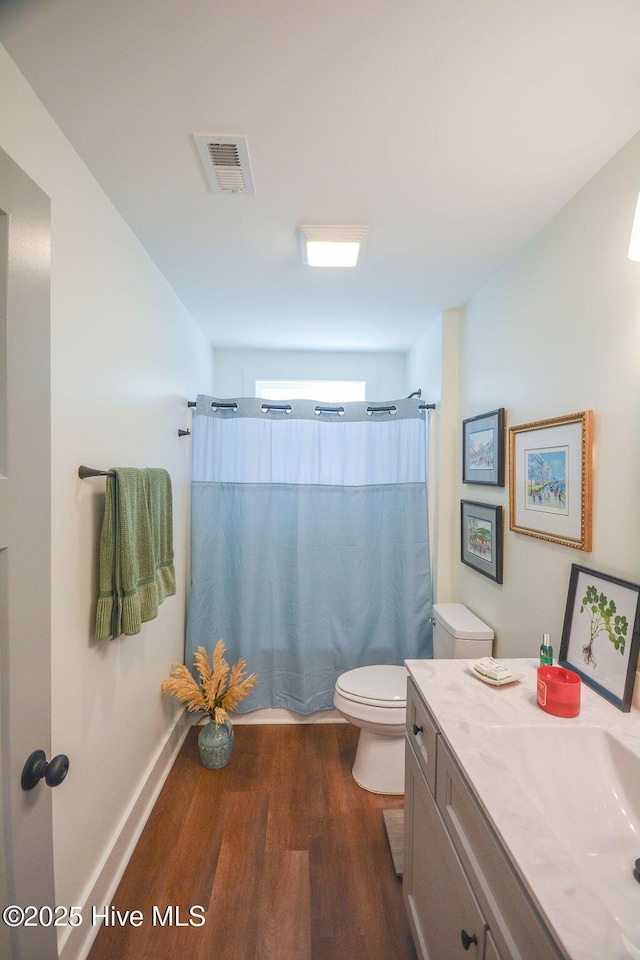 full bath featuring toilet, wood finished floors, curtained shower, visible vents, and vanity