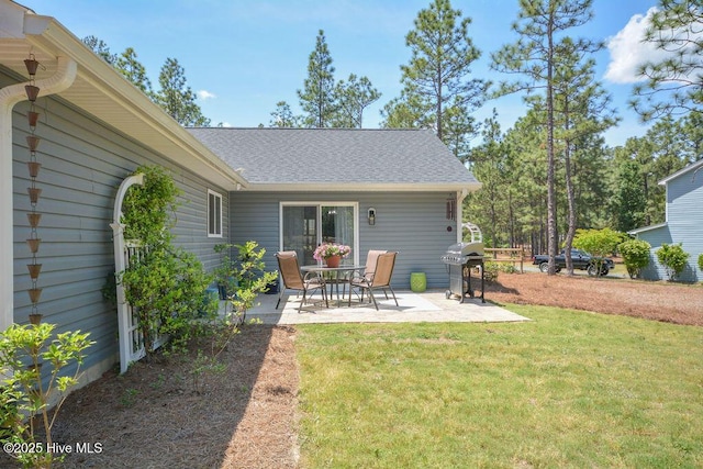 back of house featuring a yard, a patio area, and a shingled roof