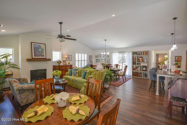 dining area with a ceiling fan, dark wood finished floors, a fireplace, and vaulted ceiling