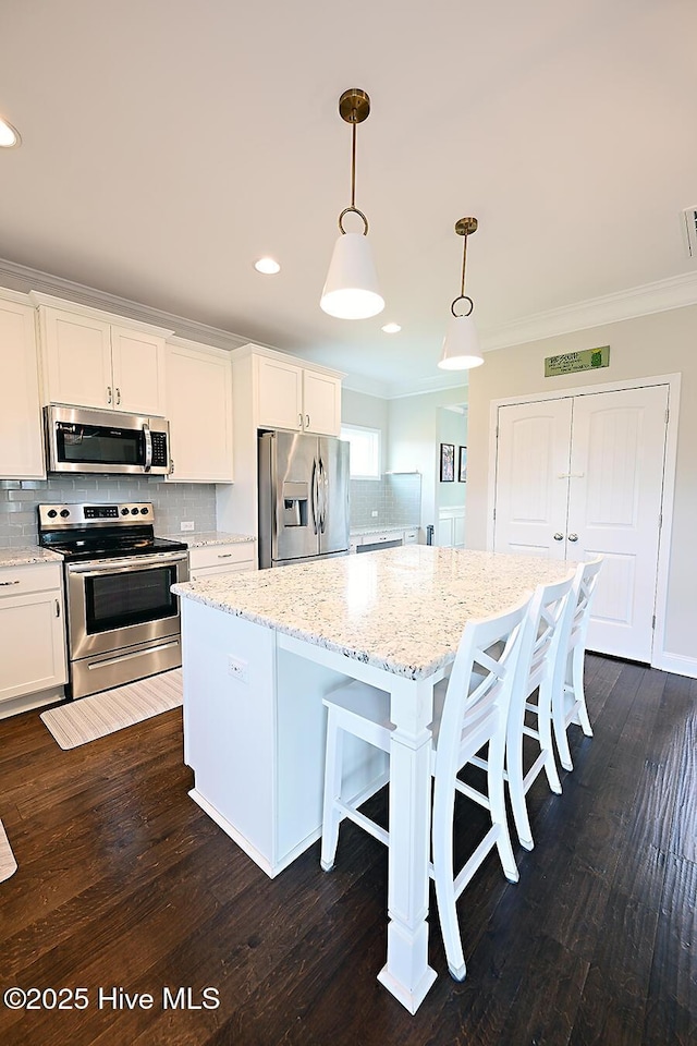 911 Needlerush Rd, Sneads Ferry, NC 28460 - kitchen with appliances with stainless steel finishes, ornamental molding, a center island, decorative backsplash, and a kitchen bar