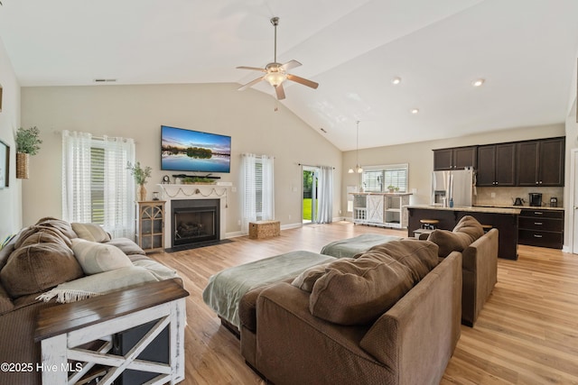 living area with light wood finished floors, high vaulted ceiling, and a ceiling fan