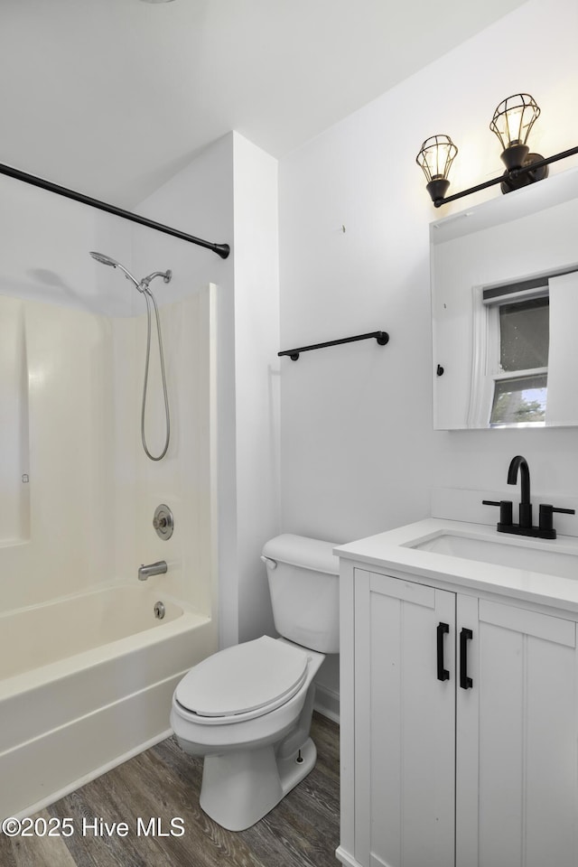 bathroom featuring toilet, tub / shower combination, wood finished floors, and vanity