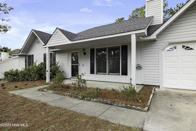 single story home featuring covered porch, roof with shingles, an attached garage, and a chimney