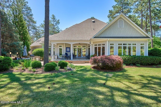 rear view of property with a yard, a ceiling fan, and a shingled roof