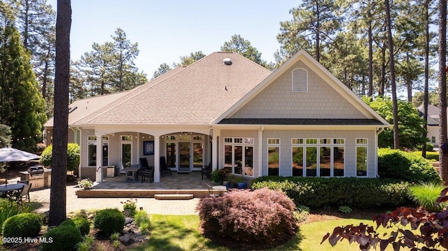 rear view of house featuring a patio area and roof with shingles