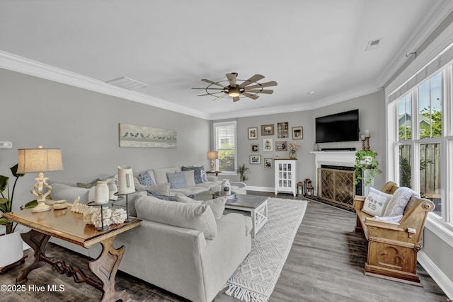 living area with visible vents, baseboards, and ornamental molding