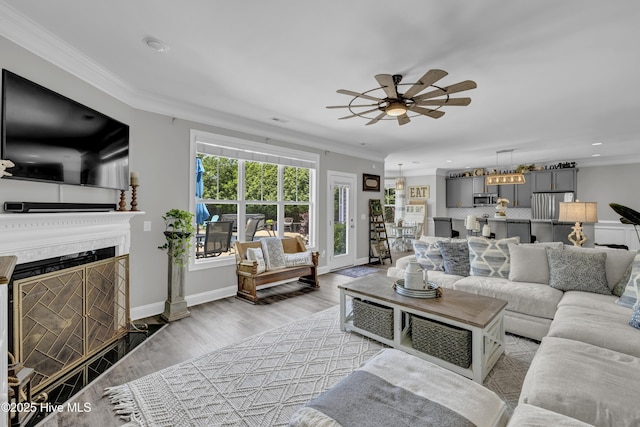 living area with crown molding, light wood-style floors, a ceiling fan, and recessed lighting
