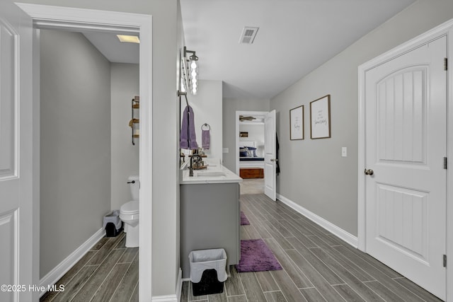 bathroom featuring baseboards, toilet, visible vents, vanity, and wood finish floors
