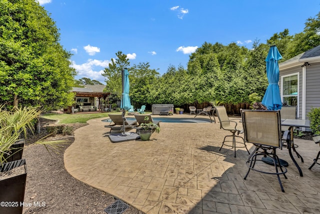 view of patio / terrace with a hot tub, a gazebo, fence, and outdoor dining area
