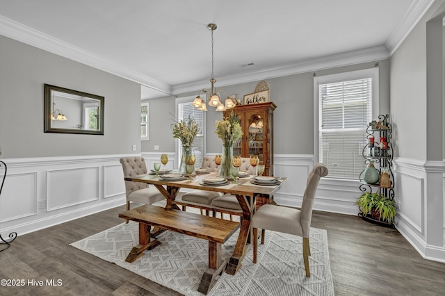 dining area featuring wainscoting, crown molding, a notable chandelier, and dark wood-type flooring