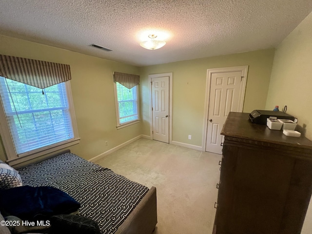 bedroom with light colored carpet, a textured ceiling, and baseboards