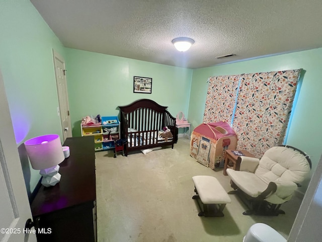 bedroom with a textured ceiling, carpet, and a crib
