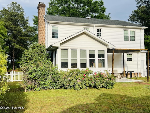 rear view of property featuring a chimney, a patio area, and a sunroom