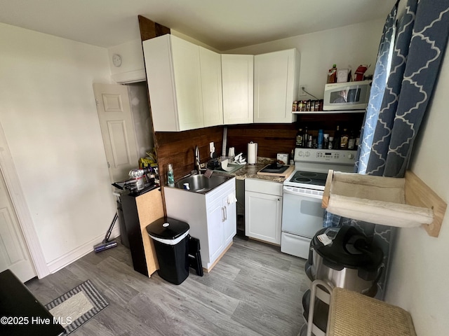 kitchen with white appliances, a sink, wood finished floors, and white cabinets