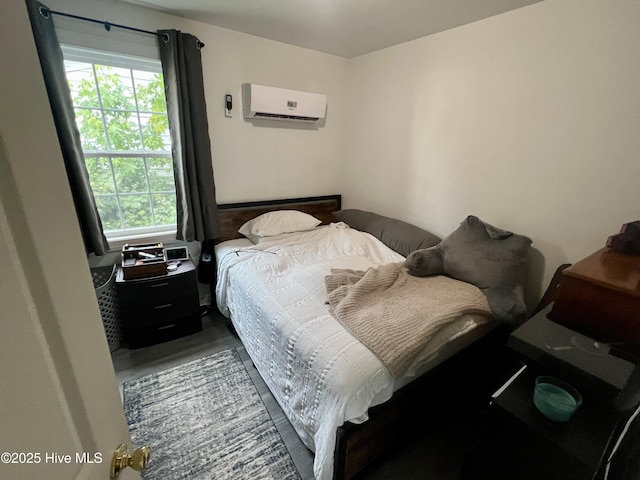 bedroom featuring a wall mounted air conditioner and wood finished floors