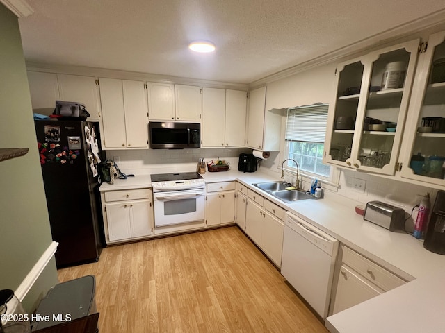 kitchen with white appliances, a sink, tasteful backsplash, light wood-style flooring, and a textured ceiling
