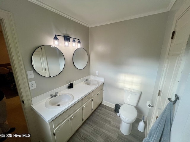 full bath featuring double vanity, toilet, crown molding, baseboards, and wood finished floors