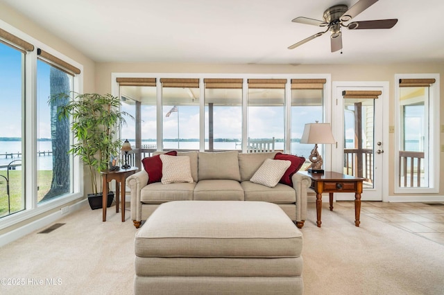 living room with a water view, visible vents, a ceiling fan, and light carpet