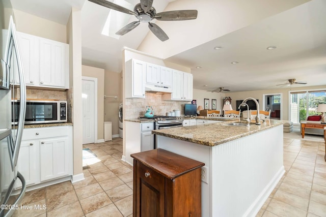 kitchen featuring a ceiling fan, open floor plan, backsplash, under cabinet range hood, and appliances with stainless steel finishes
