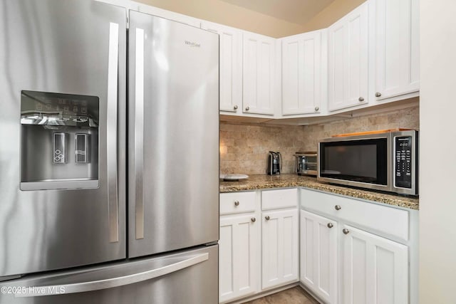 kitchen with white cabinets, stainless steel appliances, light stone counters, and backsplash