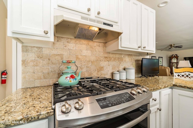 kitchen with under cabinet range hood, stainless steel gas range, ceiling fan, backsplash, and white cabinets