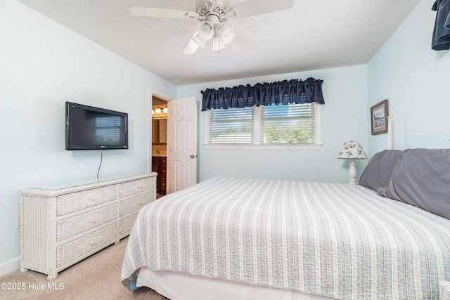 bedroom with a ceiling fan, ensuite bathroom, and light colored carpet
