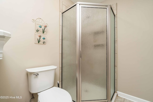 bathroom with a stall shower, tile patterned flooring, and toilet