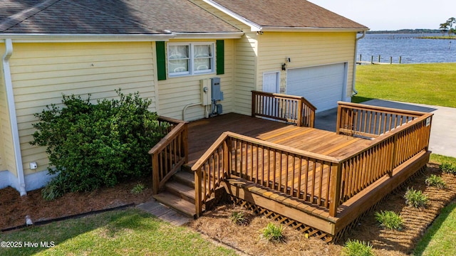 deck featuring a yard, a water view, and a garage
