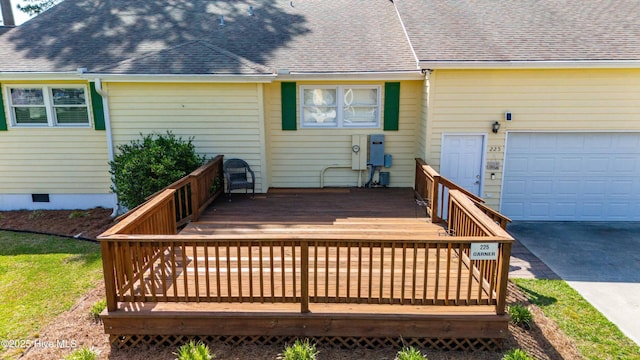 wooden terrace featuring concrete driveway and an attached garage