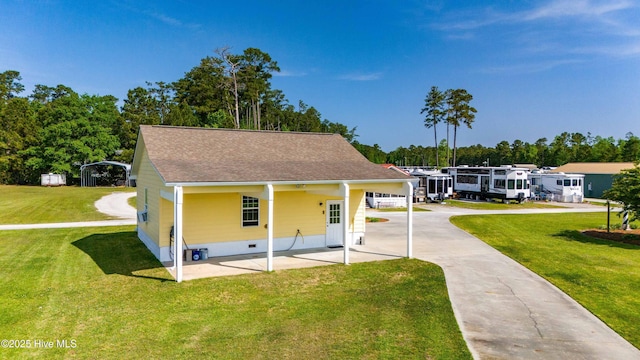 view of front of house with a carport, driveway, a front yard, a patio area, and roof with shingles