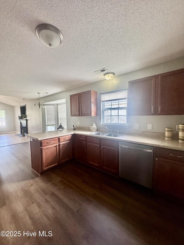 kitchen featuring a peninsula, a sink, a healthy amount of sunlight, stainless steel dishwasher, and dark wood-style floors