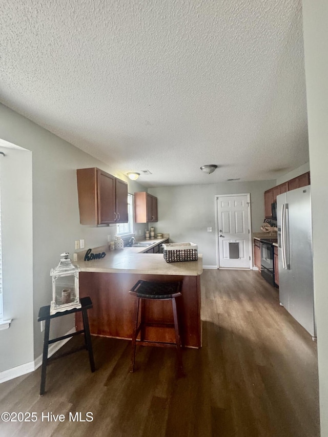 kitchen featuring a textured ceiling, dark wood-style floors, a peninsula, and stainless steel refrigerator with ice dispenser